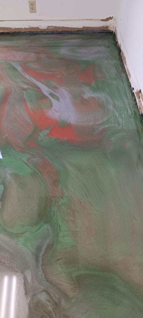 A painting of green and red paint on the wall.