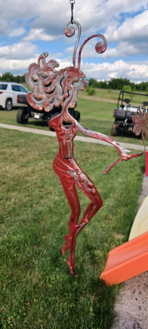 A red metal sculpture of a woman in the grass.