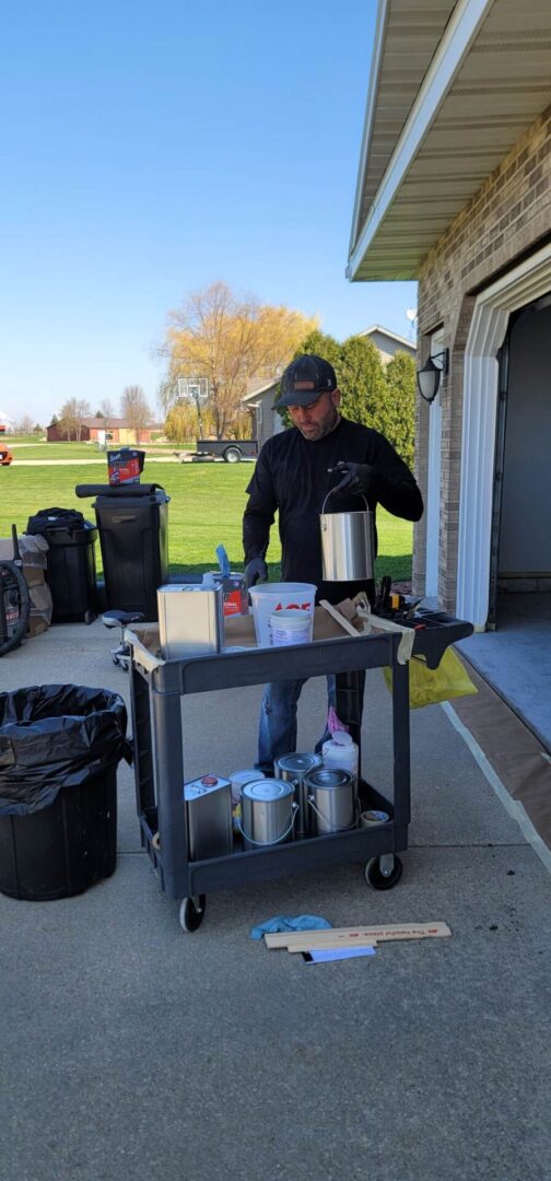 A man standing next to a cart of cans.