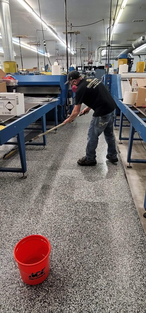 A man is cleaning the floor of an industrial building.